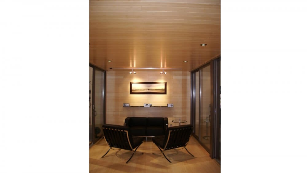 室内从地板到天花板，所有表面都采用了广泛的天然木材色调。黑色和金属家具和玻璃桌子构成了客厅空间。