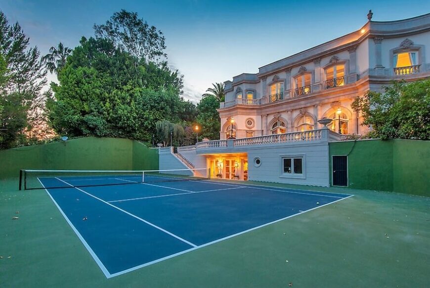 这个巨大的标准网球场有自己的入口，直接从背景中古典风格的豪宅的地下室进入。