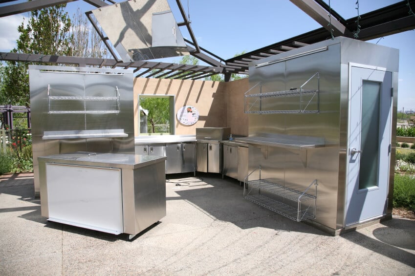 这是一个严肃的户外厨房，配有不锈钢柜台、架子和步入式冷冻室。