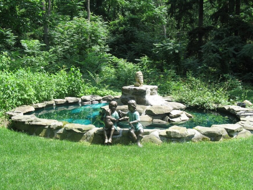 雕像可以放在池塘边，就像这些孩子和小狗的雕像，就像坐在这个人做的后院池塘边一样。