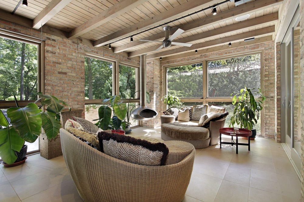 一个热带类型的阳光房，包括一些详细的椅子，砖墙，瓷砖地板，当然，一些盆栽热带植物。
