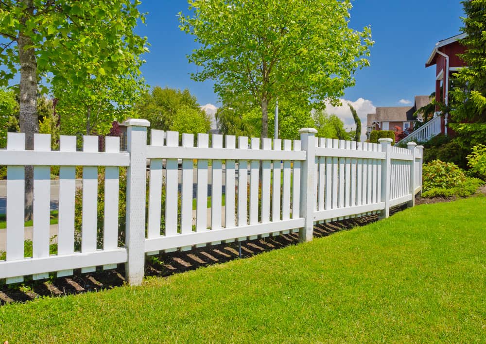 White backyard fence with decorative fence post caps
