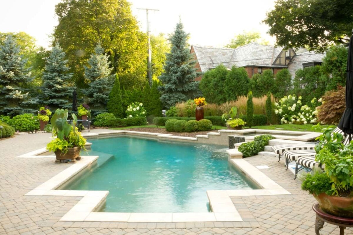 这里有一个例子，说明周围的花朵和灌木丛如何增强一个已经很漂亮的游泳池的外观。我喜欢那个带灰白色泳池边的砖砌露台。