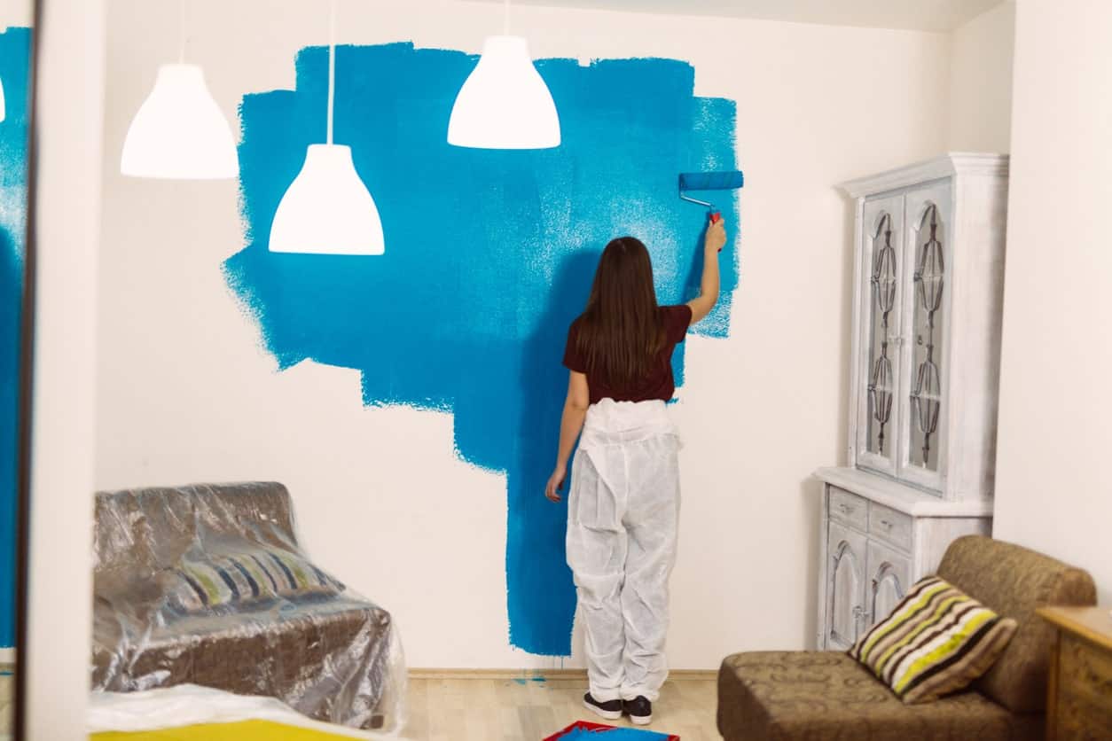 一个女人把内墙涂成蓝色的背影。