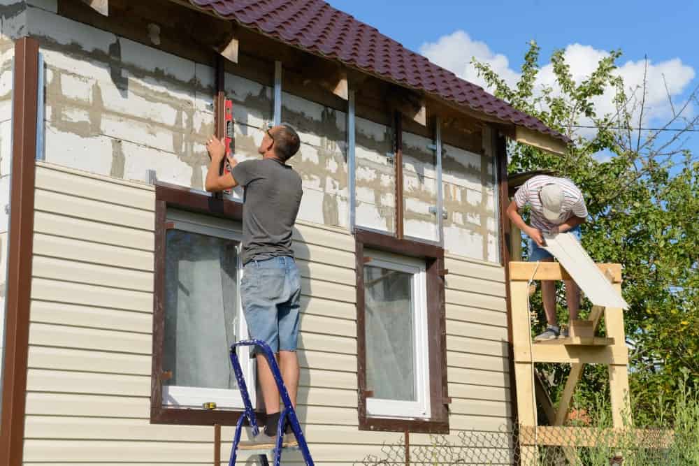 两名男子为住宅外部安装乙烯基墙板。