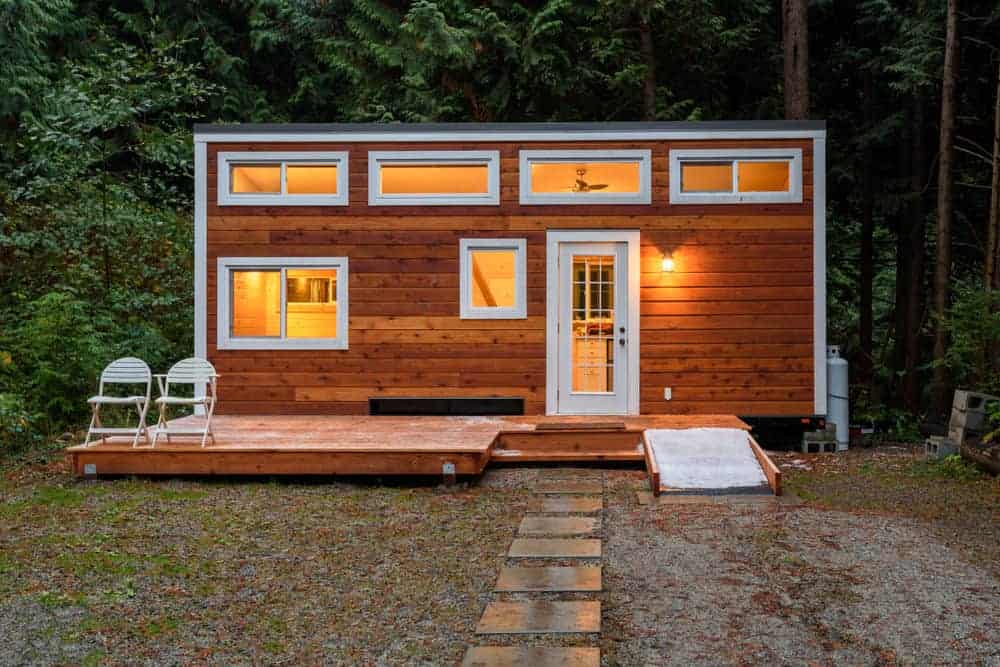 小木屋，木质外观和白色装饰。前门通向一个小平台。