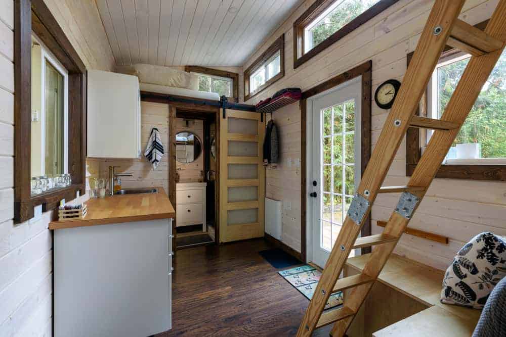 一个小木屋的内部主要生活空间，有厨房区和两个阁楼卧室，可通过梯子到达。