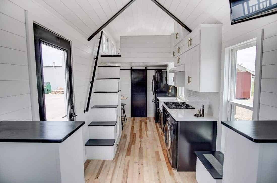 厨房和楼梯的内部照片在一个定制建造的小房子。白色的墙壁和天花板与浅色的天然木地板看起来非常棒。