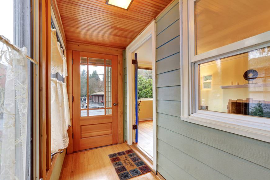 简单的玻璃前门与硬木地板和带天窗的木板天花板融为一体。