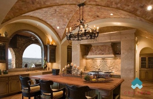 这间华丽厨房的拱形天花板由小土砖制成，与挂在厨房岛台上方的黑色锻铁枝形吊灯相得益发。这个枝形吊灯还可以用作挂锅和锅的架子。