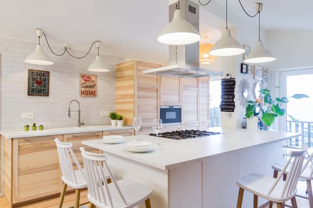这个美丽的斯堪的纳维亚风格的厨房有一个美丽的简单。它有一个迷人的裸木厨房橱柜，与浅色硬木地板完美匹配。白色的木制厨房岛台和白色的木凳使这里更加明亮。
