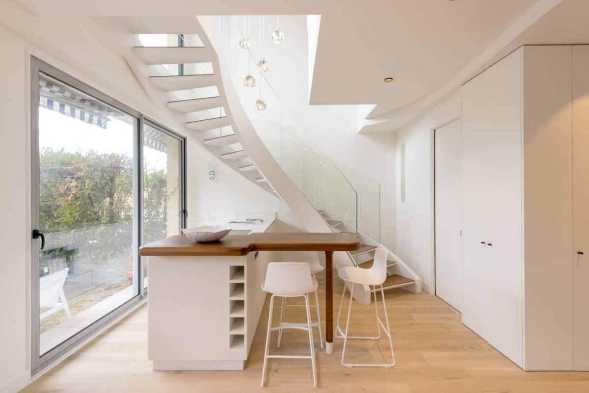 白色的小厨房靠近楼梯，面对着玻璃滑动门。