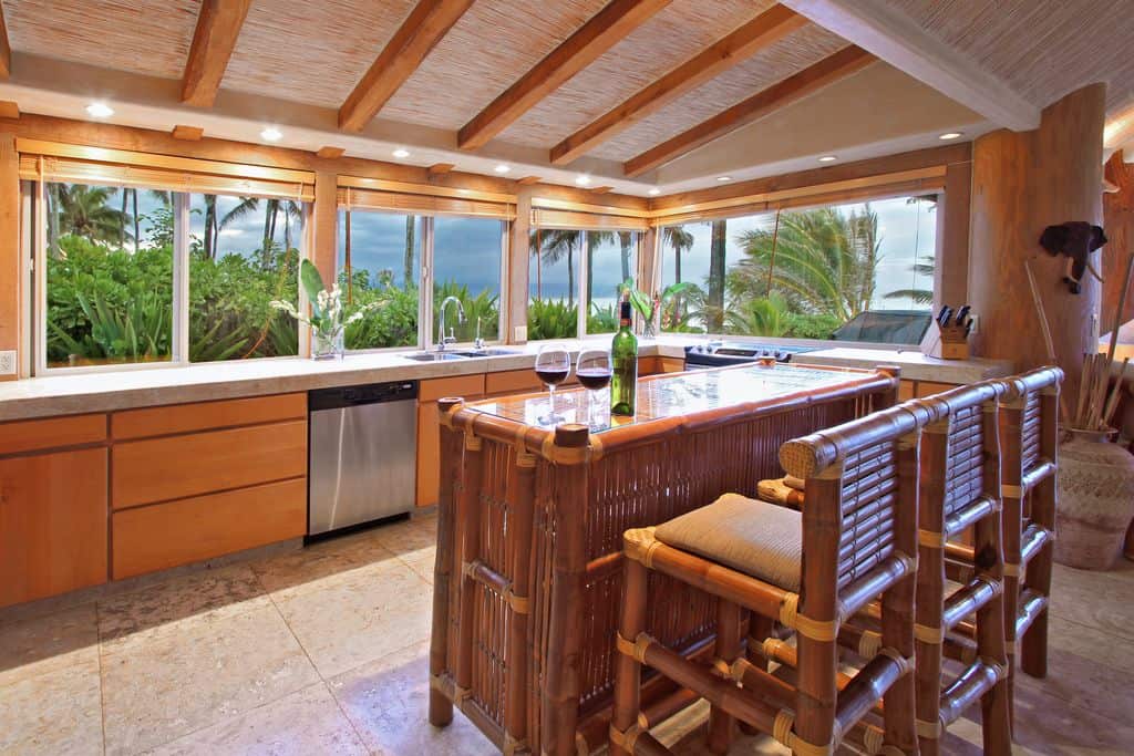 这是一个华丽的热带风格的厨房，厨房岛完全由竹子制成，并配有玻璃顶部。这与带软垫的竹凳完美搭配。这是一个很好的热带热带背景