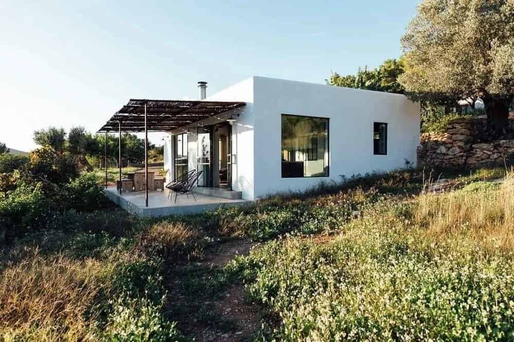 一个华丽而简单的小房子，白色的外墙使它在乡村景观周围脱颖而出。它有一个户外用餐区和木质覆盖下的休息区，以便更好地沉浸在景观中。