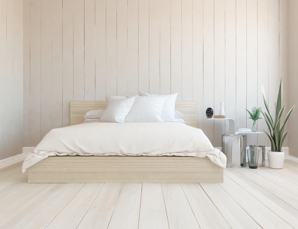 这是一个极简主义的卧室，有一个木制的平台床，与周围的木墙和地板相匹配。