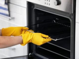 一个戴着手套拿着烤箱架的人。