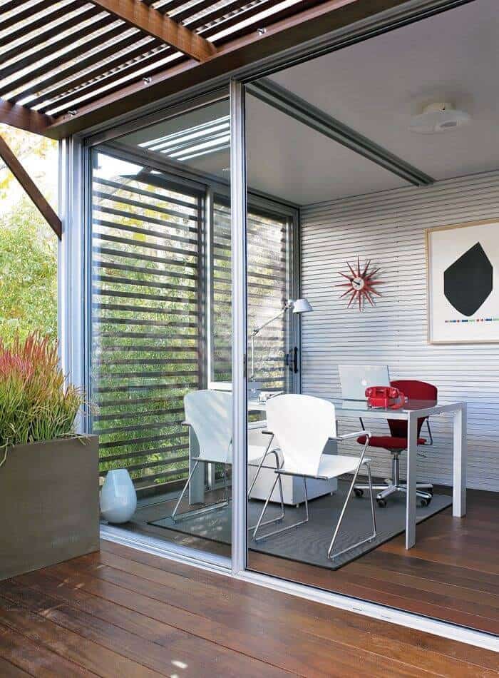 该模块配置为办公室，带有极简玻璃和金属桌，钢墙和硬木地板延伸至庭院。