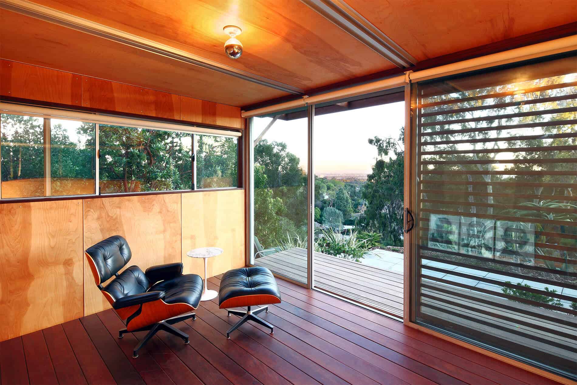 室内装饰在丰富的红色木地板与较轻的天然木墙和天花板，全玻璃视野的户外遮阳板。