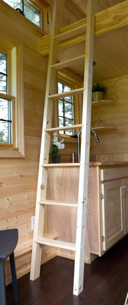 室内充满了天然的未抛光木材，厨房上方的梯子通向阁楼。