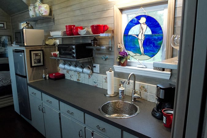 全功能厨房拥有漫长的黑色台面和水槽下彩色玻璃窗盖，电器在左边。
