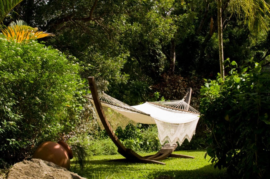 这个可爱的钩织吊床是挂在一个半圆形木架的两端。这张吊床坐落在院子里树林中一个僻静的地方。