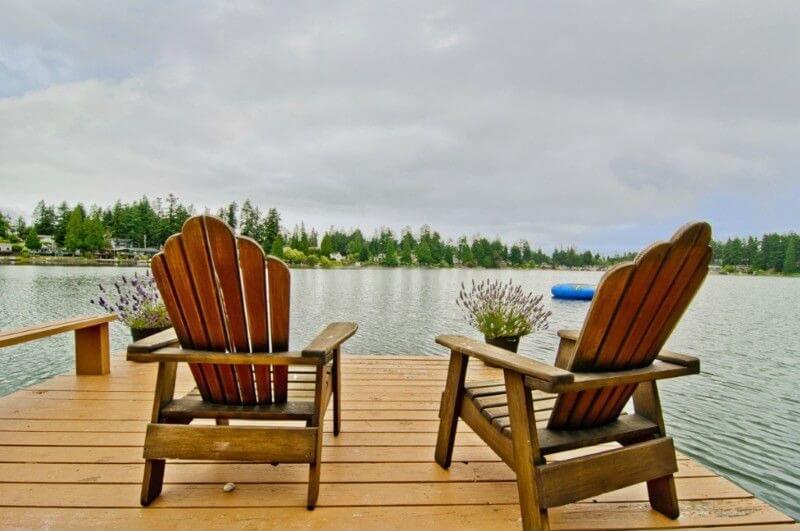 一组阿迪朗达克椅子坐在码头的尽头，旁边有两个装满薰衣草的花盆。他们眺望着一片原始、平静的湖泊。