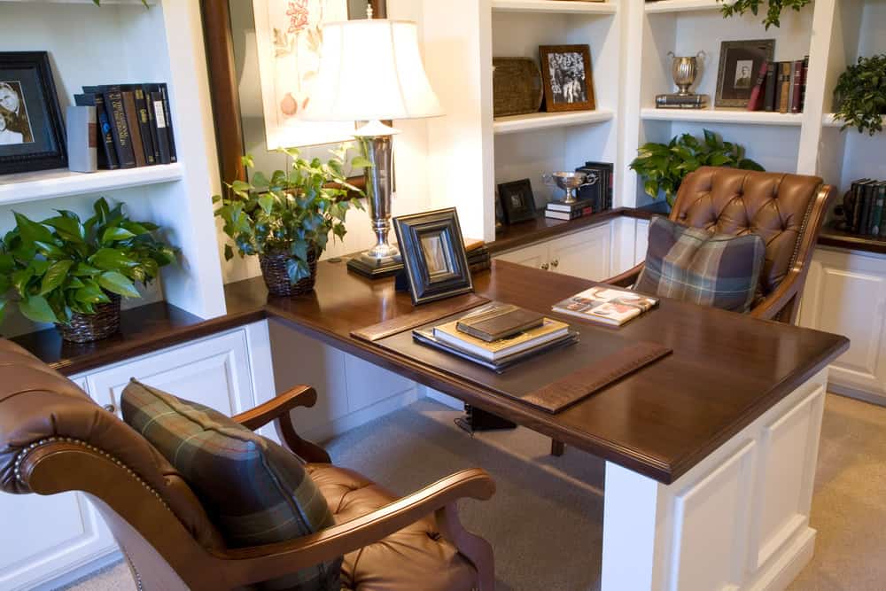 设计精美的家庭办公室，白色和棕色的桌子，植物和架子。