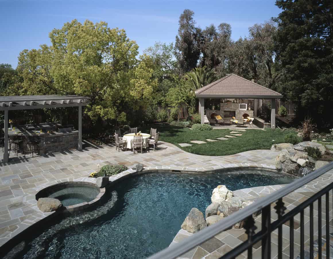 华美的自由形态游泳池与灰色石露台在可爱的后院。
