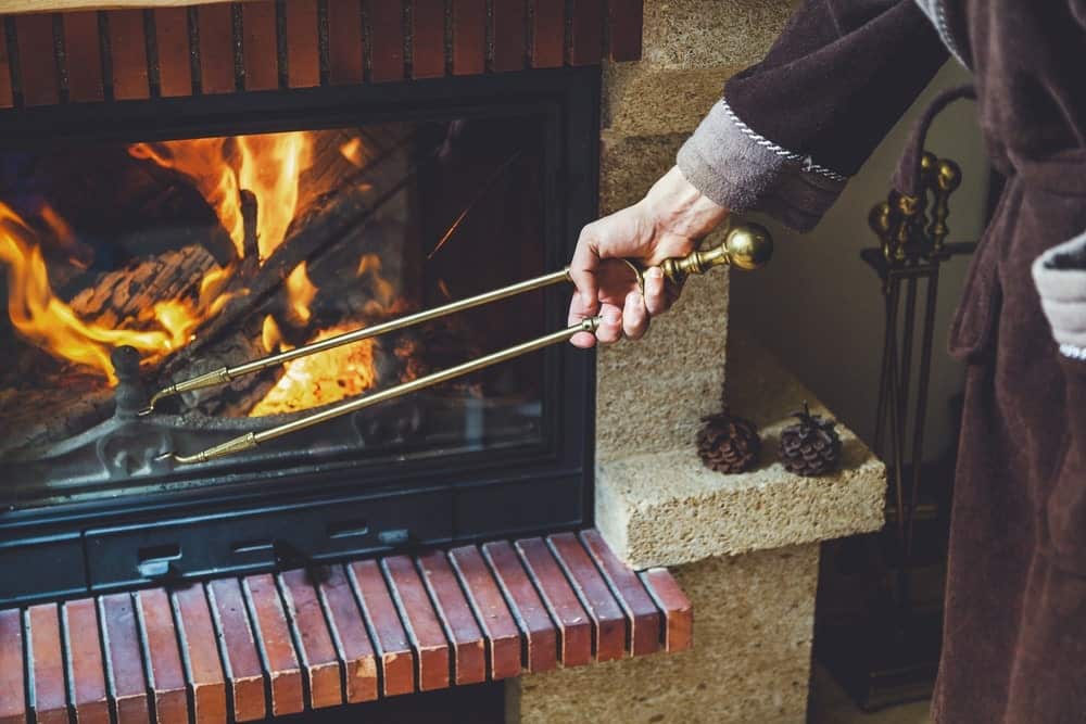 使用壁炉钳的人用于移动燃烧的火原木。