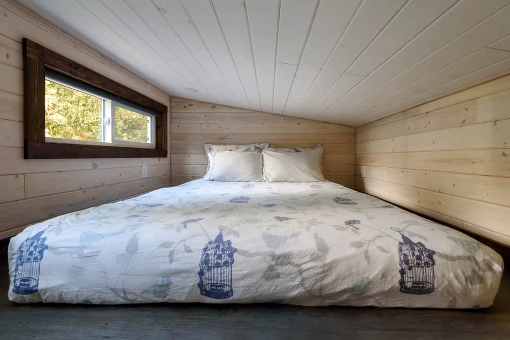 阁楼睡觉区域的照片——小木屋里的双人床。