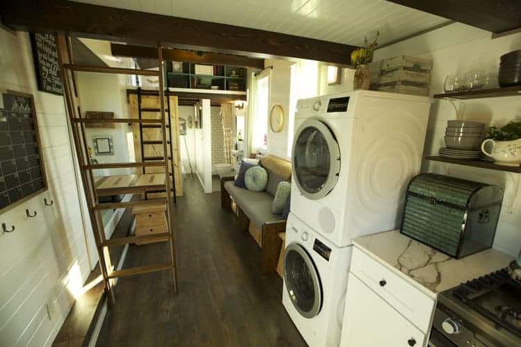 可堆叠的洗衣机和烘干机内的小房子与深色木地板。