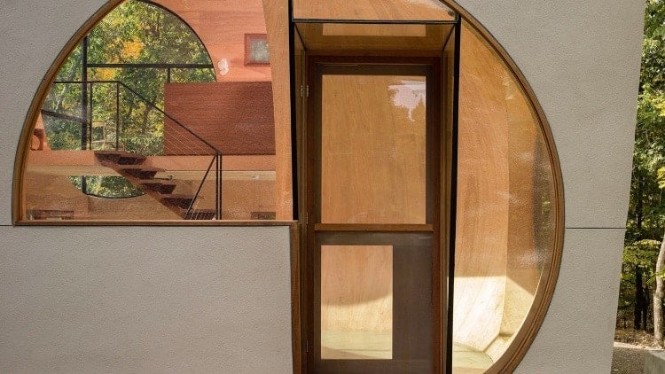 一个非传统的房子，玻璃前门与弯曲的窗户整合在一起。它的圆滑，独特的设计，使一个完美的补充迷人的森林背景。