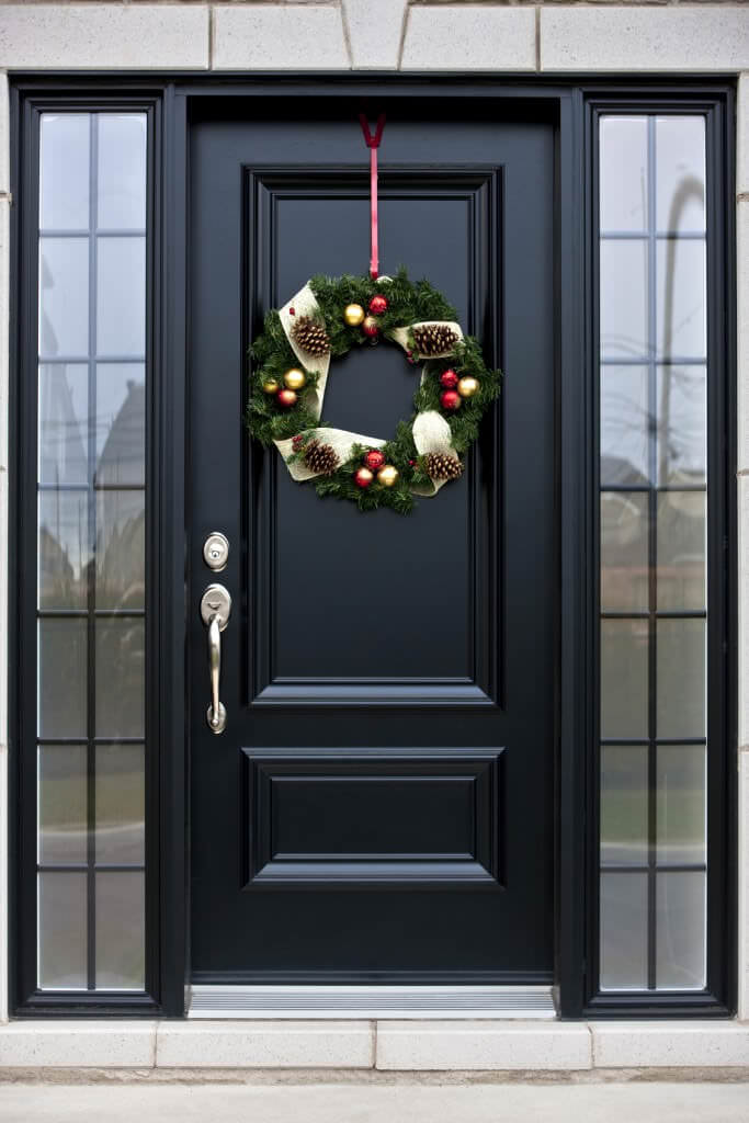一扇可爱的花圈装饰的时尚前门。它衬有黑色铝中玻璃插孔。