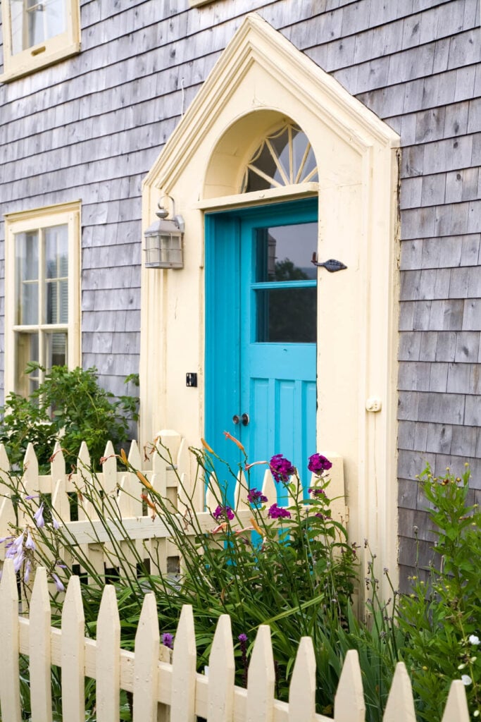 在这座房屋里，绿松石前门在浅色木材旁观者中带来了一片颜色。它是由铬丘塞和奶油栅栏包裹在绿色植物周围的补充。
