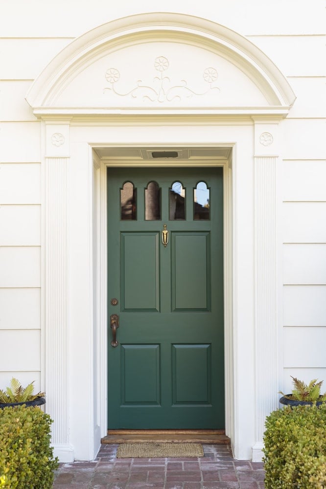 翡翠的绿色门配有拱形玻璃插孔以及青铜手柄和黄铜敲门网。它被白色柱成型包围，并设计有简约的花卉雕刻的拱形装饰开销。