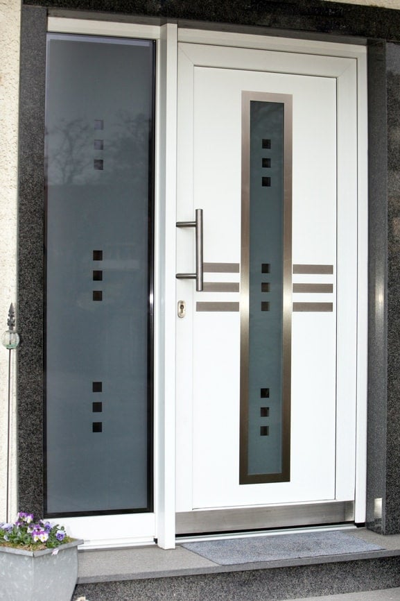 现代风格的白色前门配有光滑的镀铬手柄，与磨砂玻璃面板一起加入银色装饰。