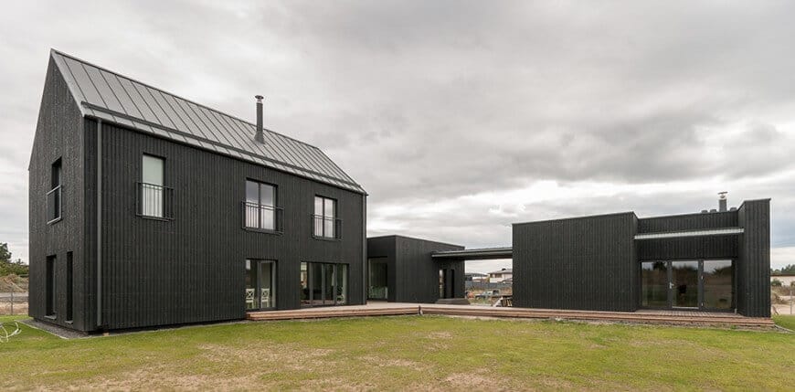 这栋房子的外观是时尚的黑色，带有露台和宽阔的草坪。